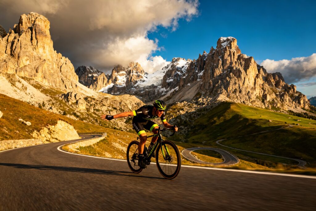 Ciclista_professionista_in_discesa_sulle_Dolomiti_con_paesaggio_alpino_drammatico